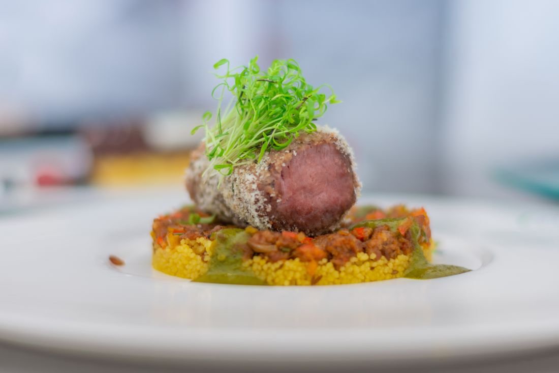 Médaillon d'agneau halal rosé sur couscous épicé et jeunes pousses — plat traiteur